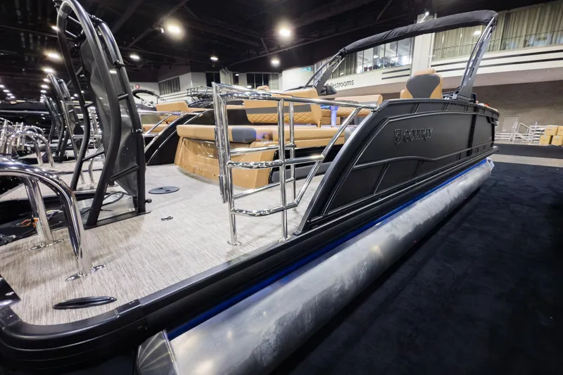 Slide: The Image of 2026 Godfrey Monaco 255 pontoon boat with luxurious seating and sleek design at an indoor exhibition. - 2