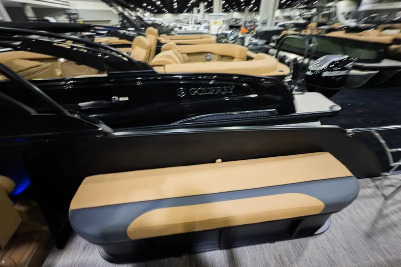 Slide: The Image of 2026 Godfrey Monaco 255 boat with tan seating and sleek black exterior at a showroom. - 26