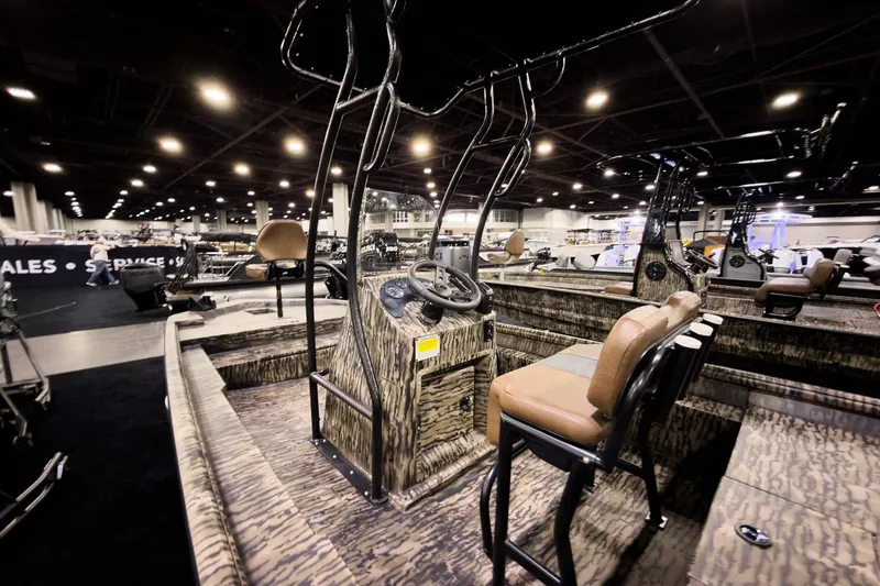 Slide: The Image of 2026 Excel 216 Stalker Center Console boat at indoor exhibition, showcasing camo design and seating. - 4