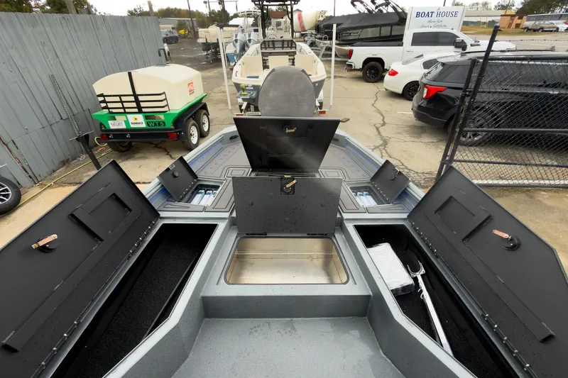Slide: The Image of 2026 Excel Bay Pro Elite 230 boat with open storage compartments in a marina setting. - 24