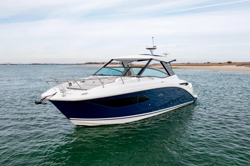 Slide: The Image of 2020 Sea Ray Sundancer 320 Outboard cruising on calm waters near a sandy shoreline. - 2