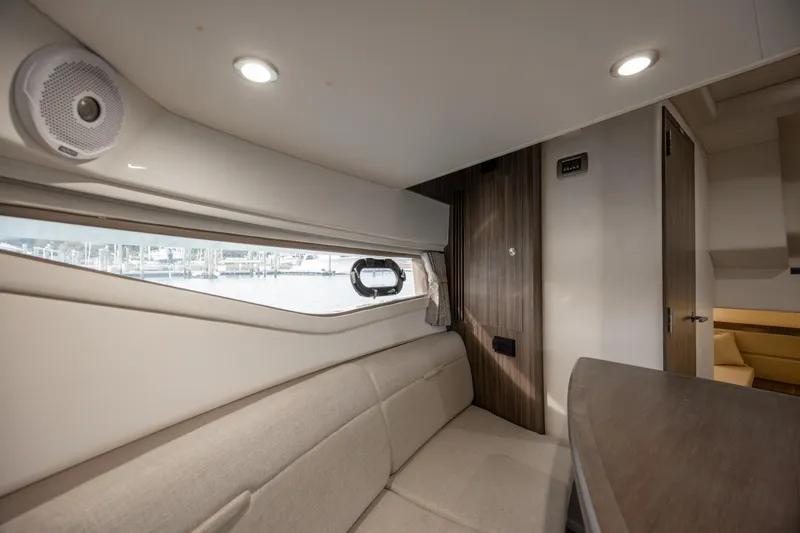 Slide: The Image of 2020 Sea Ray Sundancer 320 Outboard cabin interior with beige seating and wood accents. - 48