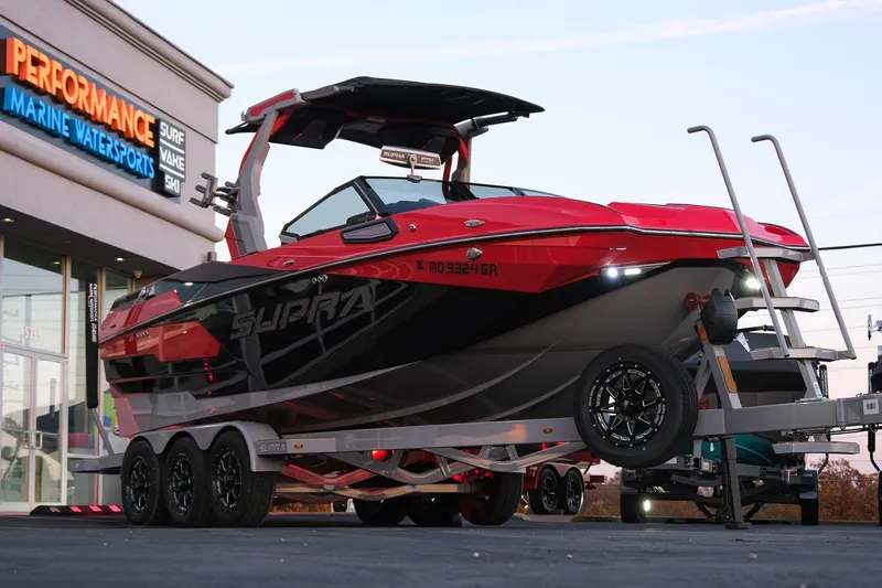 Slide: The Image of 2025 Supra SE boat in red and black on a trailer at Performance Marine Watersports. - 8