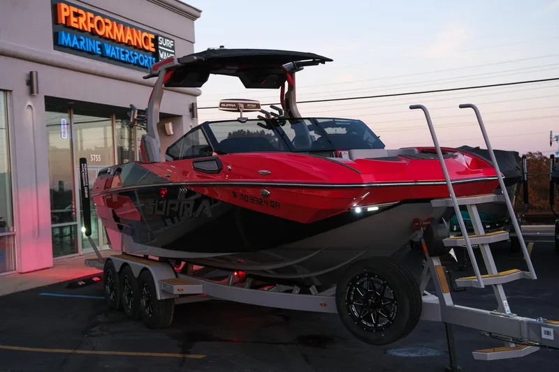 Slide: The Image of 2025 Supra SE boat on trailer at Performance Marine Watersports dealership. - 9