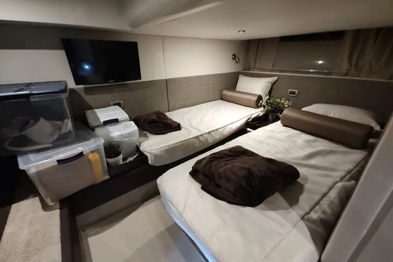 Slide: The Image of 2017 Sea Ray Sundancer 400 cabin with twin beds, TV, and storage containers. - 21