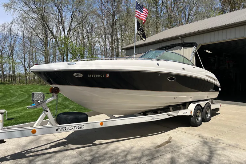 The Image of 2003 Chaparral Signature 260 boat on trailer, parked outdoors near a garage. - 0