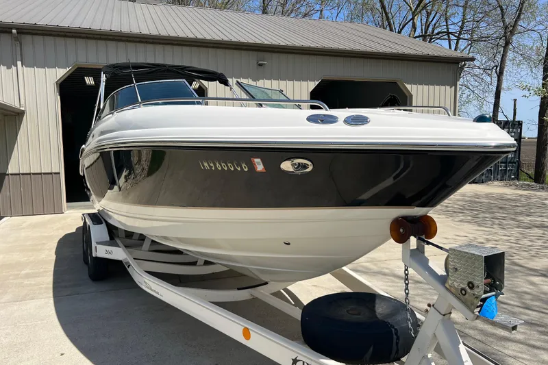 Slide: The Image of 2003 Chaparral Signature 260 boat on trailer, parked outside a garage. - 2