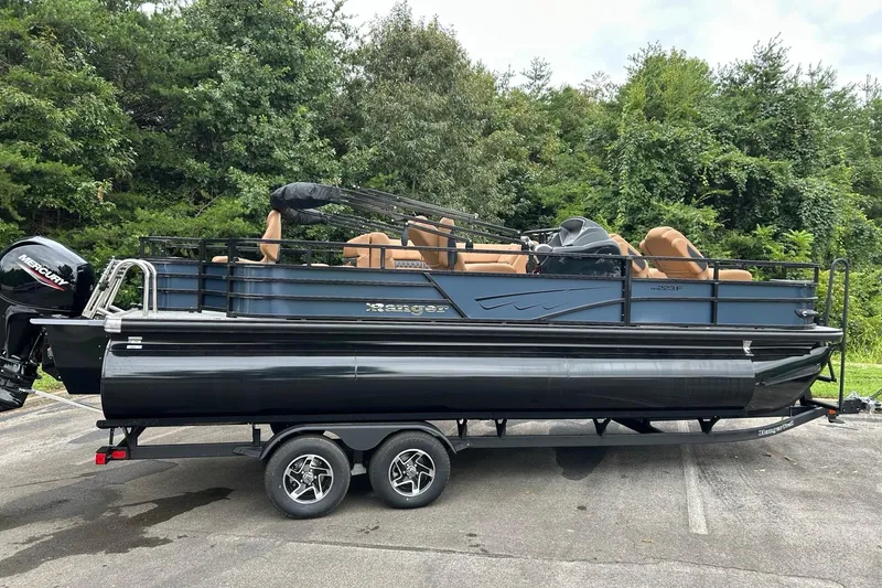 The Image of 2026 Ranger 223F pontoon boat on trailer, parked outdoors with lush greenery background. - 0