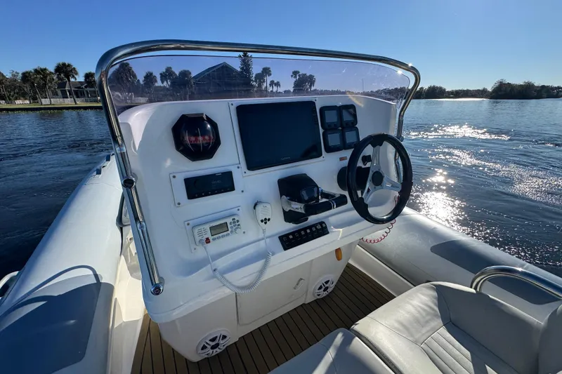 Slide: The Image of 2010 Cobra Ribs Nautique 8.6m boat dashboard with steering wheel and controls on water. - 11