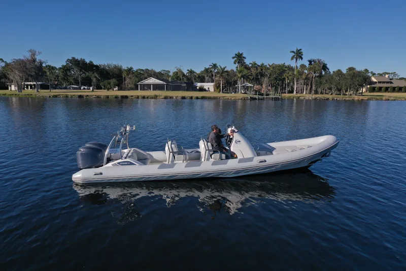 Slide: The Image of 2010 Cobra Ribs Nautique 8.6m boat on calm water, surrounded by trees and houses. - 3