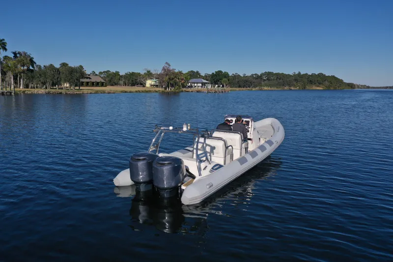 Slide: The Image of 2010 Cobra Ribs Nautique 8.6m boat on serene lake with clear blue sky. - 4