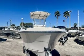 Slide: The Image of 2019 Cobia 237 Center Console boat on trailer, clear sky, palm trees in background. - 2