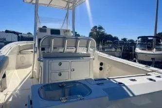 Slide: The Image of 2019 Cobia 237 Center Console boat with spacious deck and seating, under clear blue sky. - 6
