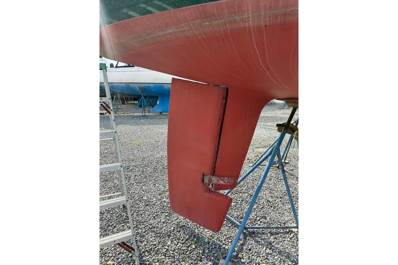 Slide: The Image of Red rudder of a 2000 Outbound 44 sailboat on a gravel lot. - 78