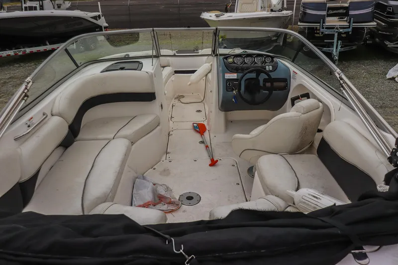 Slide: The Image of 2006 Yamaha Boats SX210 interior with seating and steering wheel, docked outdoors. - 9