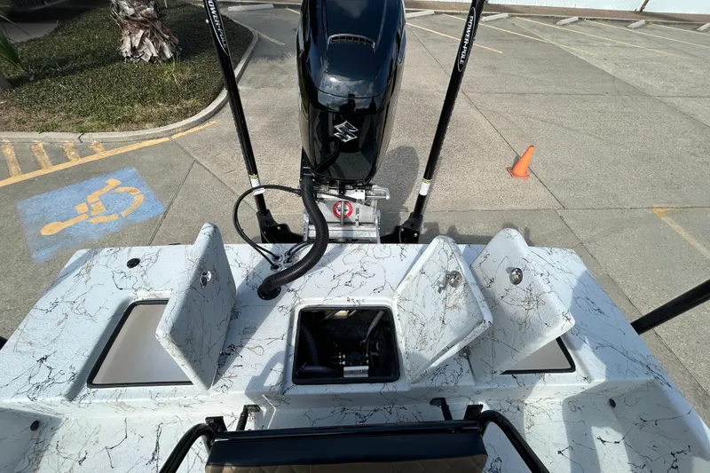 Slide: The Image of 2026 Skuta 24 Vista boat with open storage compartments and outboard motor in a parking area. - 10