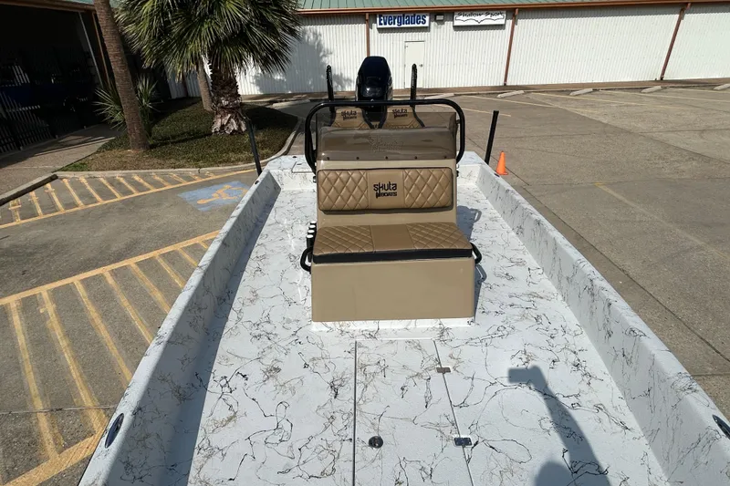 Slide: The Image of 2026 Skuta 24 Vista boat with marble-patterned deck and tan seating, parked outdoors. - 17