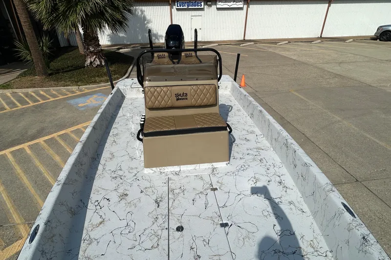 Slide: The Image of 2026 Skuta 24 Vista boat with marble-patterned deck and tan seating, parked outdoors. - 18