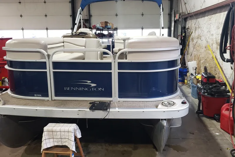 Slide: The Image of 2014 Bennington 22SSX pontoon boat in a garage, blue and white design. - 0