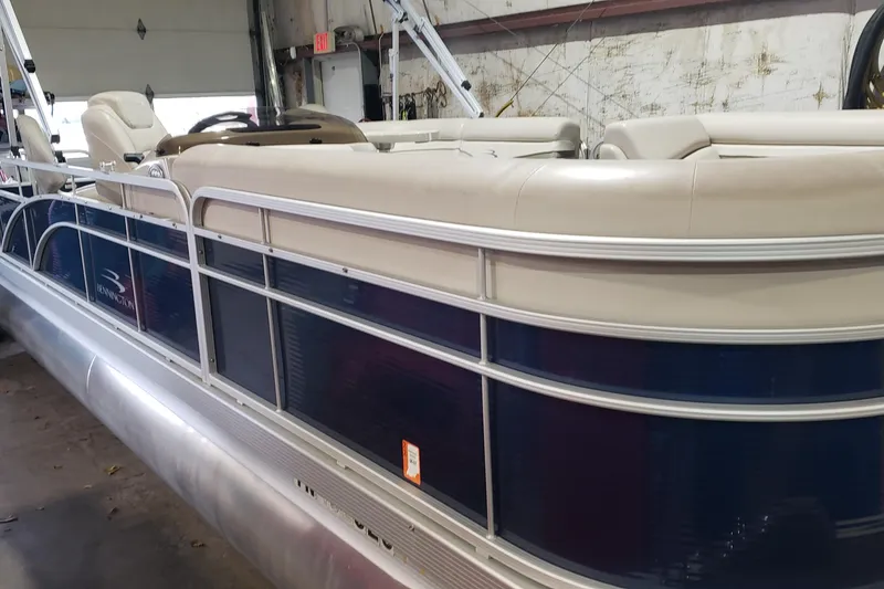 Slide: The Image of 2014 Bennington 22SSX pontoon boat in a garage, featuring beige seating and blue paneling. - 1