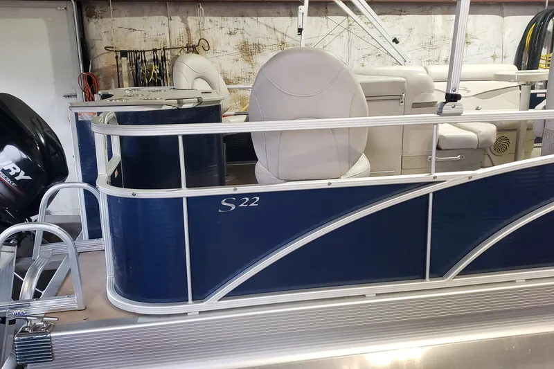 Slide: The Image of 2014 Bennington 22SSX pontoon boat with blue exterior and white seating in a garage. - 2