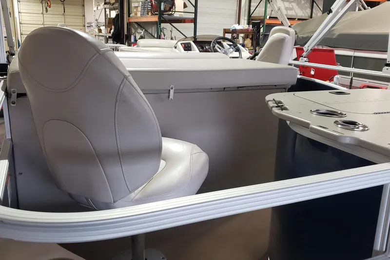 Slide: The Image of 2014 Bennington 22SSX boat interior with beige seating and cup holders in a showroom. - 6