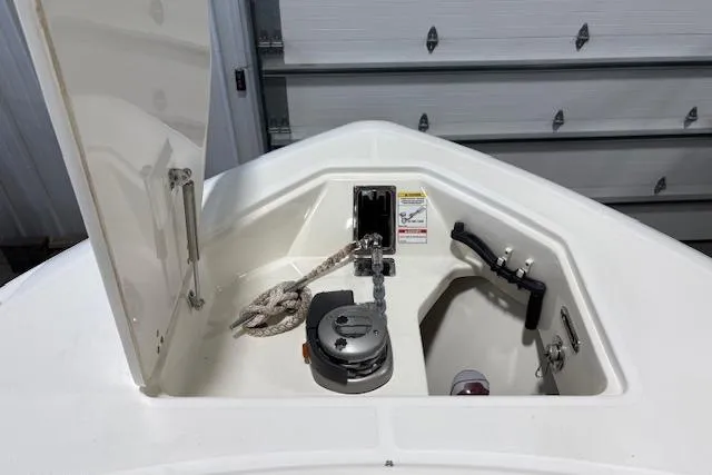 Slide: The Image of 2020 Boston Whaler 330 Outrage anchor compartment with rope and winch in a garage setting. - 23