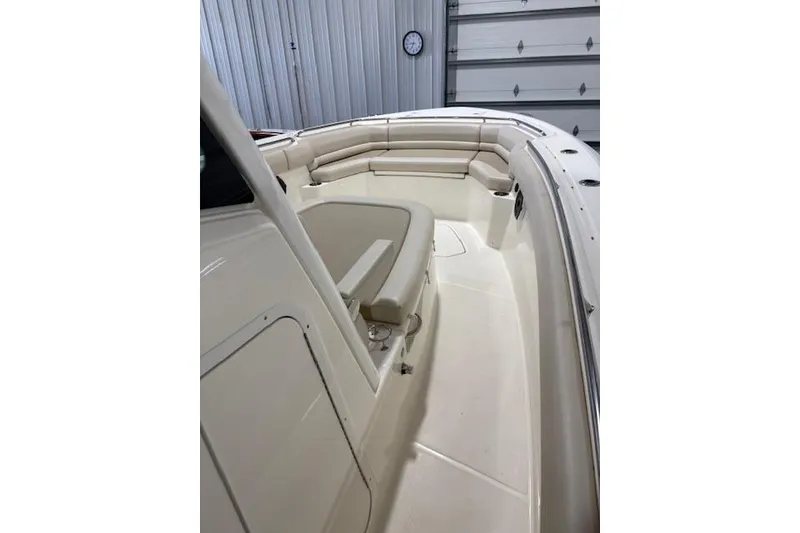 Slide: The Image of 2020 Boston Whaler 330 Outrage boat interior with cushioned seating in a garage setting. - 25