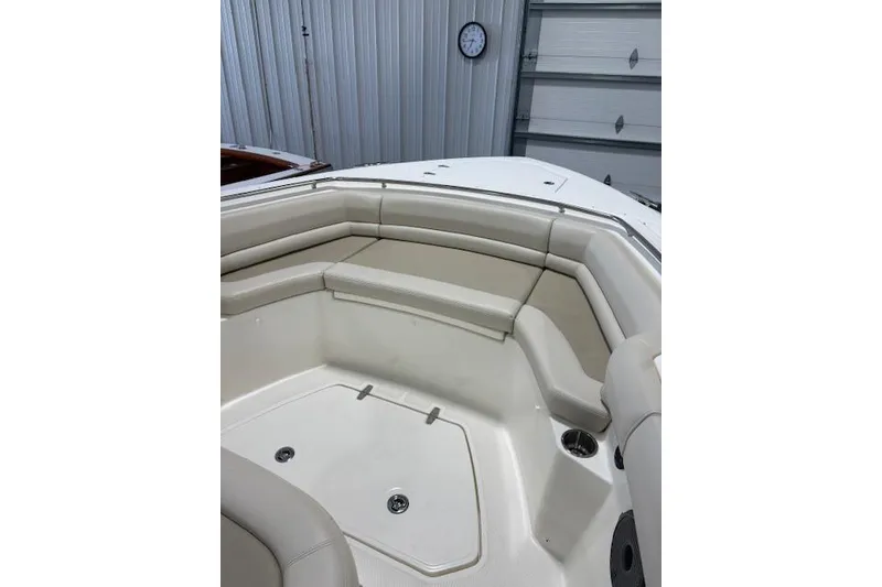 Slide: The Image of 2020 Boston Whaler 330 Outrage boat interior with cushioned seating in a garage setting. - 28