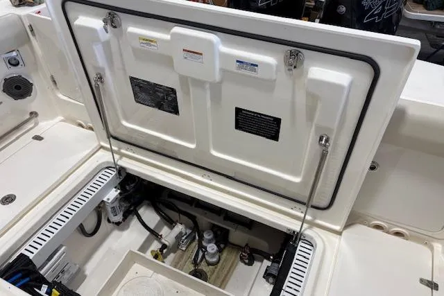 Slide: The Image of 2020 Boston Whaler 330 Outrage boat compartment with open hatch, showcasing internal components. - 29