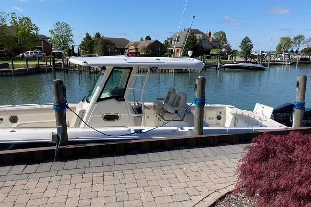 Slide: The Image of 2020 Boston Whaler 330 Outrage docked by a scenic waterfront with clear skies. - 3
