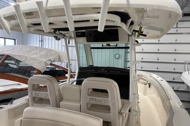 Slide: The Image of 2020 Boston Whaler 330 Outrage boat interior with helm and seating in a garage. - 34