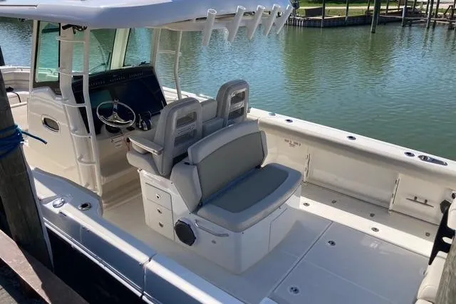Slide: The Image of 2020 Boston Whaler 330 Outrage boat interior with seating and helm, docked by the water. - 5