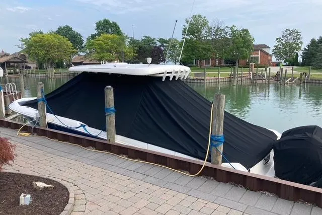 Slide: The Image of 2020 Boston Whaler 330 Outrage covered at dockside, surrounded by calm water and greenery. - 7