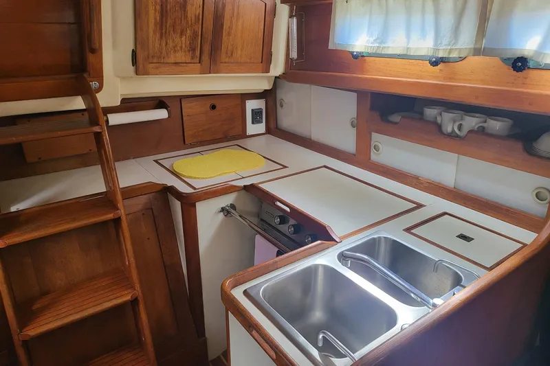 Slide: The Image of 1984 Sea Sprite 34 yacht kitchen with wooden cabinets, dual sink, and compact stove. - 24