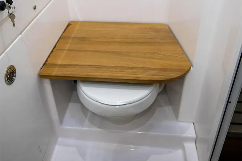 Slide: The Image of Manufacturer Provided Image: 2024 Everglades 395 Center Console boat bathroom with wooden toilet cover. - 54