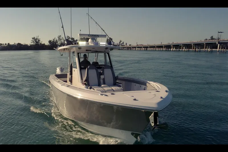 Slide: The Image of 2024 Everglades 395 Center Console boat cruising on calm waters near a bridge. - 6