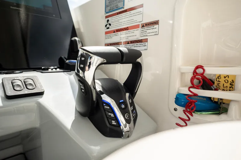 Slide: The Image of 2024 Pursuit OS 325 Offshore boat controls with warning labels and safety equipment. - 10