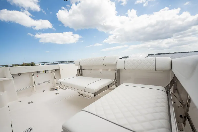 Slide: The Image of 2024 Pursuit OS 325 Offshore boat interior with white cushioned seating under a blue sky. - 14
