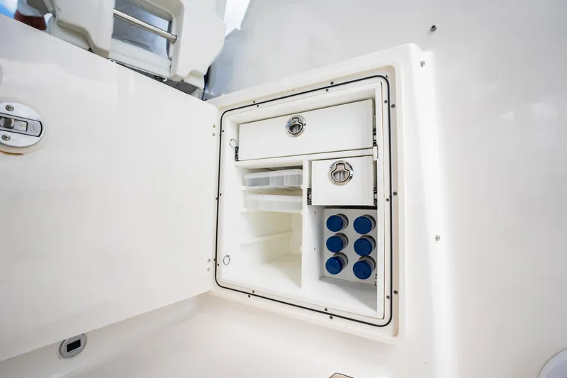 Slide: The Image of 2024 Pursuit OS 325 Offshore boat storage compartment with organized shelves and secure latches. - 18
