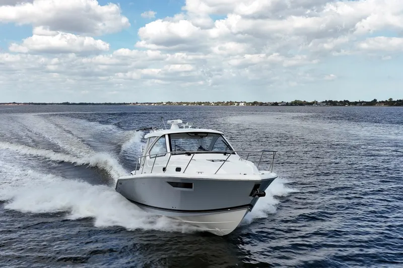 Slide: The Image of 2024 Pursuit OS 325 Offshore cruising on open water under a partly cloudy sky. - 2