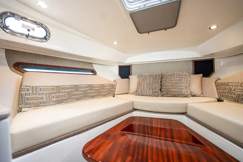 Slide: The Image of 2024 Pursuit OS 325 Offshore cabin interior with plush seating and elegant wood table. - 22
