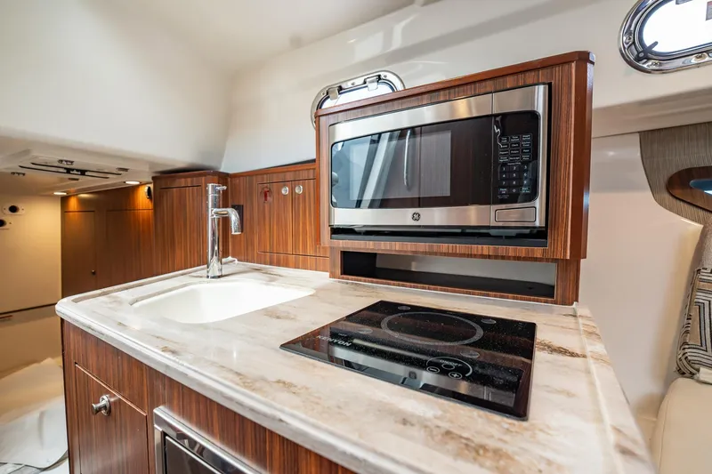 Slide: The Image of Luxurious 2024 Pursuit OS 325 Offshore yacht kitchen with modern appliances and elegant wood finish. - 26