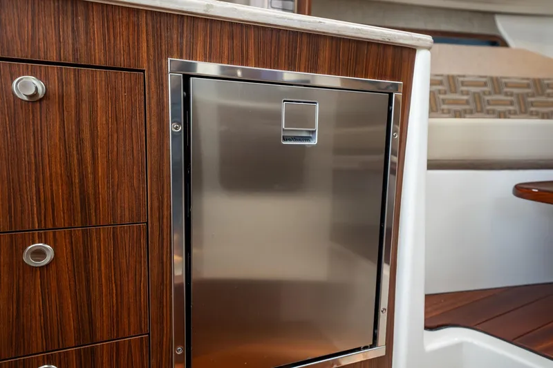 Slide: The Image of 2024 Pursuit OS 325 Offshore interior with stainless steel fridge and wood cabinetry. - 27