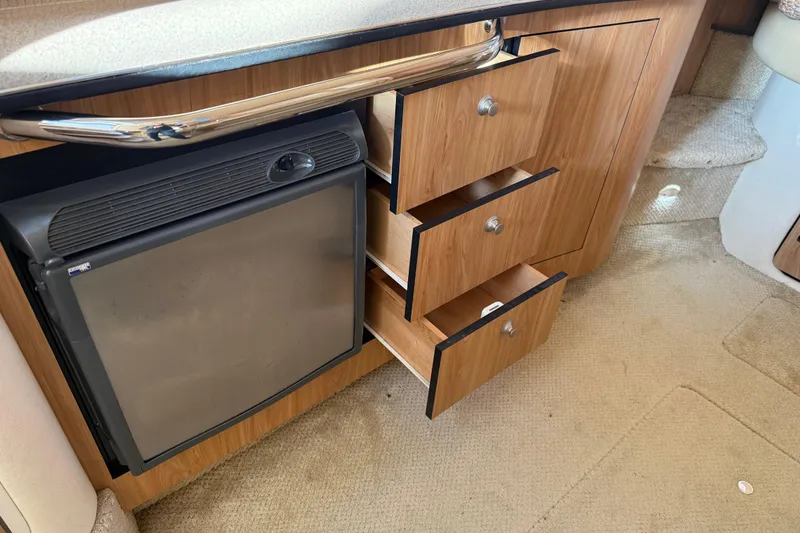 Slide: The Image of 2006 Sea Ray Sundancer 320 interior with open wooden drawers and compact fridge. - 35