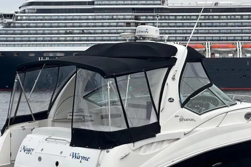 Slide: The Image of 2006 Sea Ray Sundancer 320 yacht with black canopy, docked near a large cruise ship. - 54