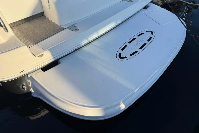 Slide: The Image of 2006 Sea Ray Sundancer 320 swim platform with logo, docked on calm water. - 57