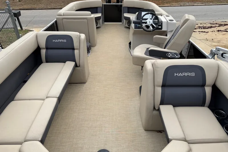 Slide: The Image of 2025 Harris Cruiser 230 boat interior with beige and gray seating, steering console, and cup holders. - 3
