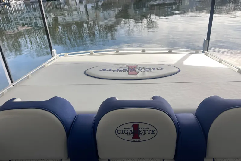 Slide: The Image of 1998 Cigarette 38' Top Gun boat interior with branded seating and deck, docked by water. - 18