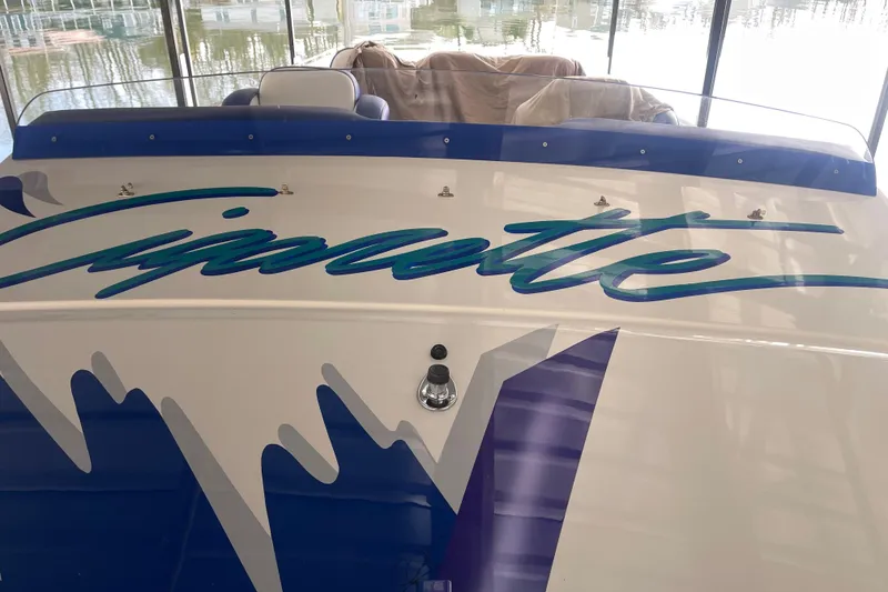 Slide: The Image of 1998 Cigarette 38' Top Gun boat with blue and white design in a marina. - 57